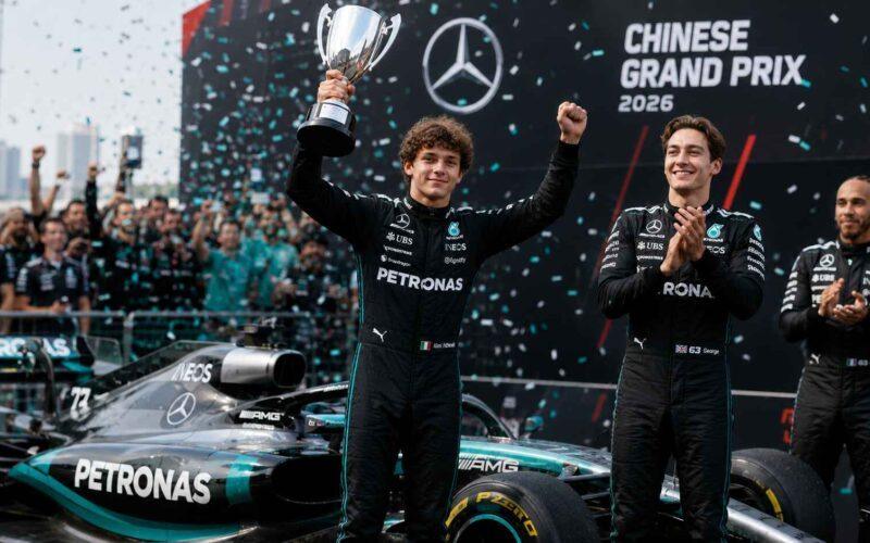 Trois pilotes en combinaisons noires Mercedes sur le podium du Grand Prix de Chine 2026. Un homme brandit un trophée.